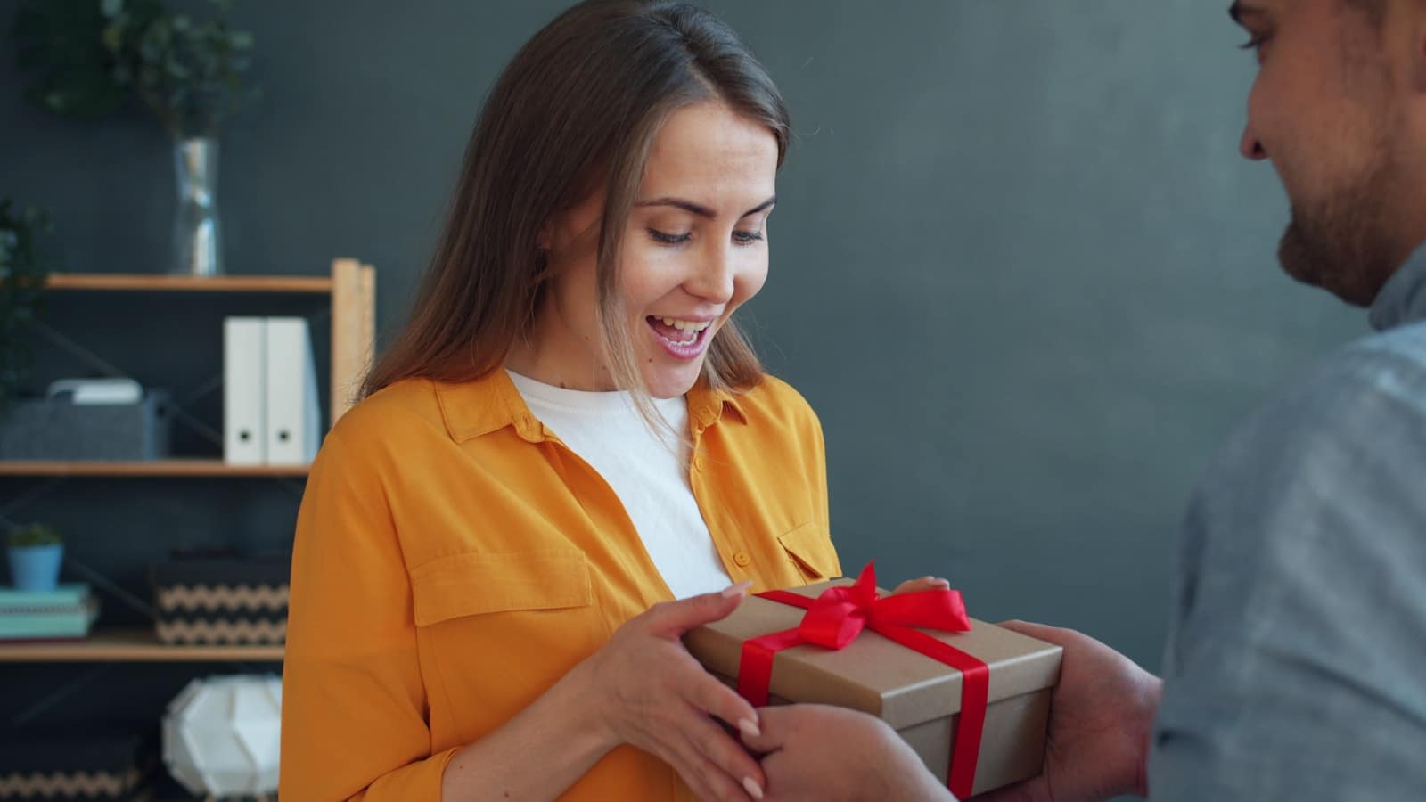 Un homme offre un cadeau à une femme souriante, pour illustrer la formule Essentiel de l'accompagnement de doula à Saint-Blaise, près de Neuchâtel